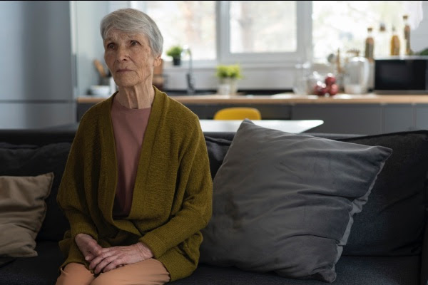 Older woman sitting on the sofa looking anxious, sad